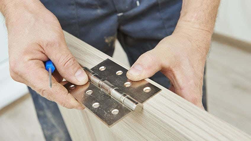 a worker adding a door hinge