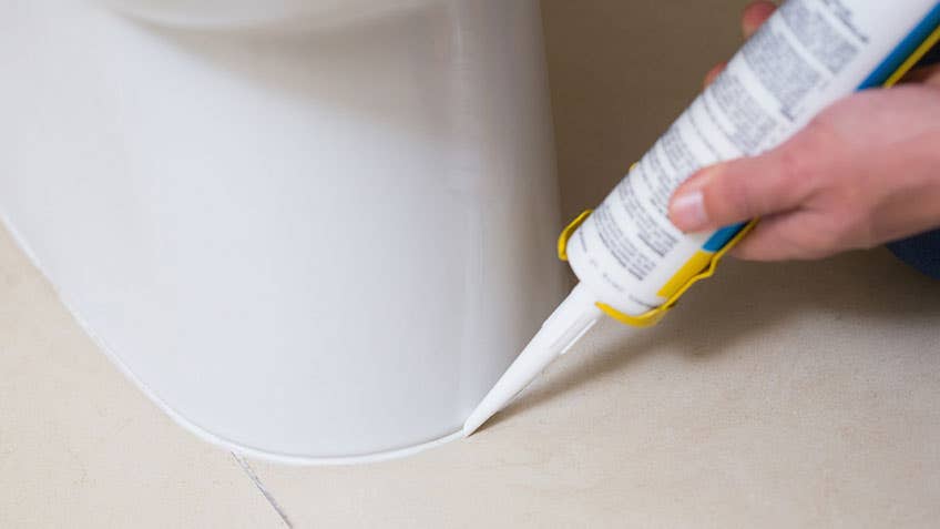 Person applying silicone sealant in a bathroom